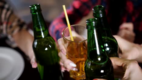 The-company-of-beautiful-girls-in-the-pizzeria-clinking-bottles-of-beer,-Close-up.