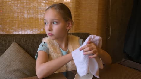 Young-woman-girl-sitting-at-the-table-in-cafe-and-wiping-her-hands-with-a-wet-towel-and-preparing-to-eat-sushi.