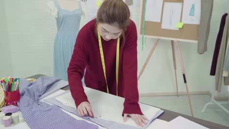 Profesional-hermosa-asiática-mujer-diseñadora-de-moda-trabajando-con-bocetos-de-la-tela-y-dibujo-diseño-de-ropa-en-el-estudio.-Mujeres-del-estilo-de-vida-que-trabajan-concepto.