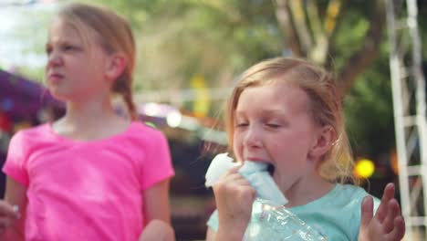 Drei-kleine-Mädchen-Essen-Zuckerwatte-und-machen-lustige-Gesichter,-die-in-Zeitlupe