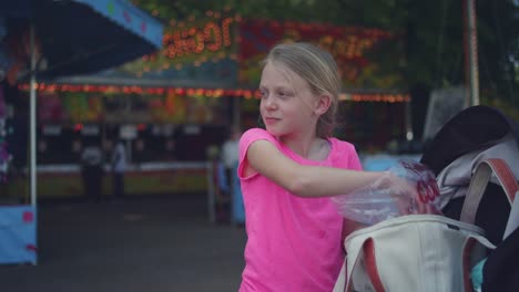 Ein-junges-Mädchen-bekommt-Zuckerwatte-Sie-eine-Tasche-und-teilt-diese