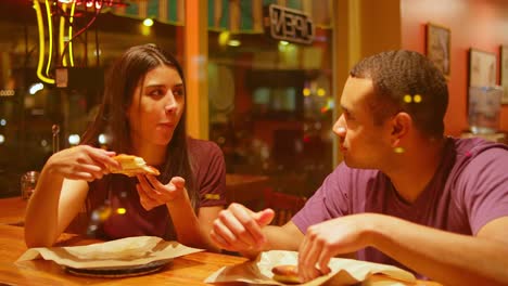 Una-joven-pareja-comiendo-en-un-centro-de-la-ciudad-de-pizzeria