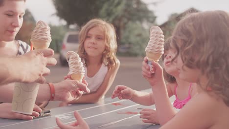 Un-padre-manos-de-un-helado-conos-un-sus-hijos-en-la-mesa-de-día-de-campo