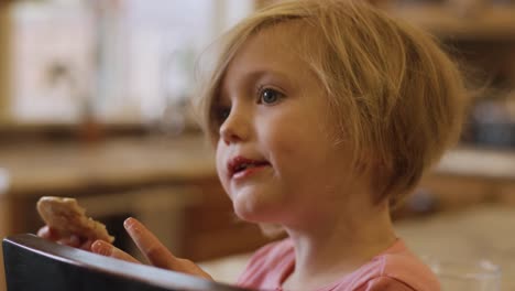 Una-niña-comiendo-un-panqueque-con-las-manos,-de-cerca,-a-cámara-lenta