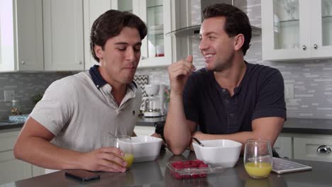 Man-feeds-his-partner-a-berry-and-checks-tablet-at-breakfast,-shot-on-R3D