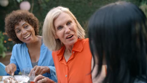 Mature-Female-Friends-Enjoying-Outdoor-Meal-In-Garden