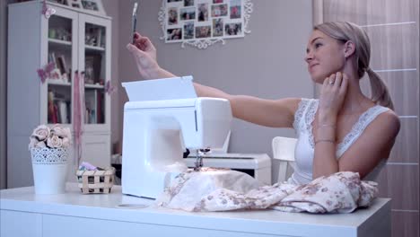 Young-woman-taking-selfies-with-her-phone-while-sitting-next-to-sewing-machine