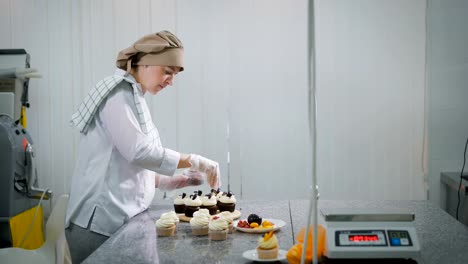 La-mujer-cocina-pasteles-para-un-día-de-fiesta.-A-la-niña-el-orden-como-la-tienda-de-golosinas-es-pequeñas-empresas.-Los-pasteles-son-preparados-en-una-mesa.-En-un-cupcakes-de-chocolate-y-fruta-de-mesa