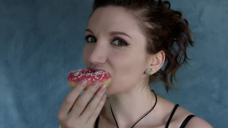 4-k-Aufnahme-einer-Frau-posiert-im-Studio-und-Essen-einen-Donut