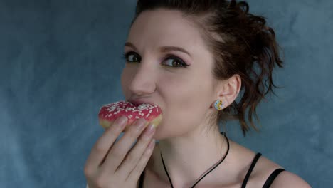 4-tiro-de-k-de-una-mujer-posando-en-el-estudio-y-comiendo-un-Donut