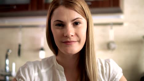 Beautiful-attractive-casual-young-woman-sitting-in-her-kitchen-smiling.-Happy-and-relaxed-at-home