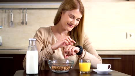 Hermosa-mujer-atractiva-desayunando,-usando-su-reloj-inteligente.-Navegando-por-Internet.-Leer-noticia