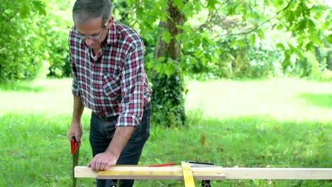 Carpenter-sawing-a-wooden-square-with-a-wood-saw