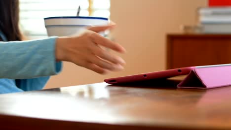 Woman-having-cereal-while-using-digital-tablet