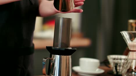 Barista-gemahlenen-Kaffee-hinzufügen-und-gießt-heißes-Wasser