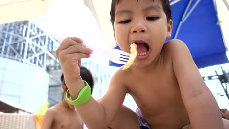 Chico-asiático-está-comiendo-papas-fritas-en-la-playa