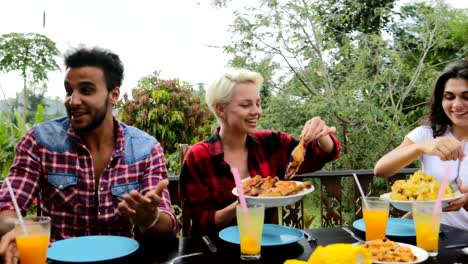 People-Passing-Food-Eating-On-Terrace-Young-Friends-Talking-Sitting-At-Table-Outdoors-Communication