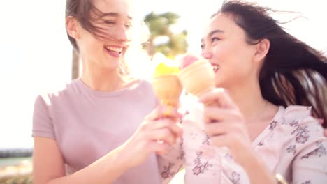 Female-best-friends-walking-and-eating-ice-cream-on-summer-holidays