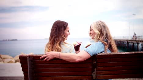 Mother-and-daughter-eating-ice-cream-and-chatting-by-the-sea