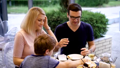 Glückliche-Eltern-und-ihr-Kind-zusammen-im-Restaurant-Pizza-genießen-und-Lachen-des-Vaters-Geschichte