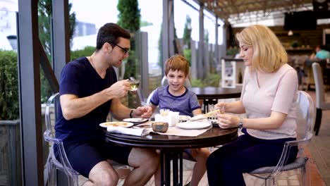 Familia-está-disfrutando-de-la-comida-todos-juntos-en-el-restaurante,-riendo-y-charlando-con-los-demás