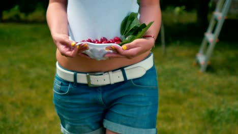 Mujer-joven-con-cerezas-en-camiseta-caminar-descalzo-sobre-la-hierba