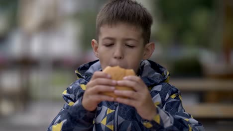 grave-joven-adolescente-comer-hamburguesa-sentado-en-la-cafetería-en-la-ciudad-de