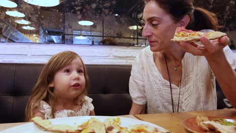 niña-y-la-madre-en-restaurante-comiendo-pizza