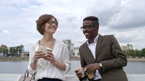 Woman-Having-Wrap-and-Coffee-while-Chatting-with-Colleague-Outdoor