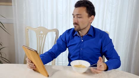 Man-eats-cornflakes-and-looks-at-the-tablet
