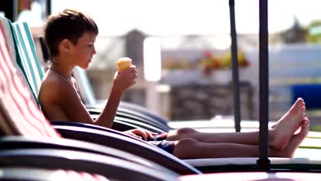 Junge,-ein-Eis-essen,-auf-einer-Liege-am-Pool-im-hotel