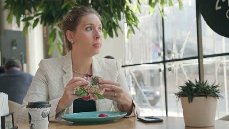 Una-señora-joven-comiendo-Sandwich-en-la-cafetería