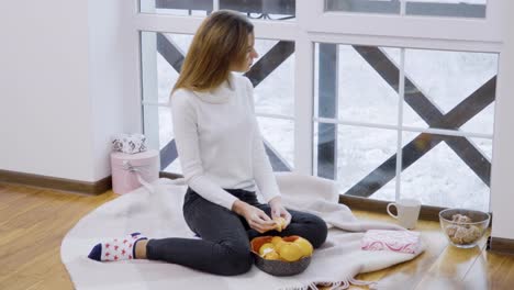 Young-girl-eats-mandarin-enjoying-a-winter-view