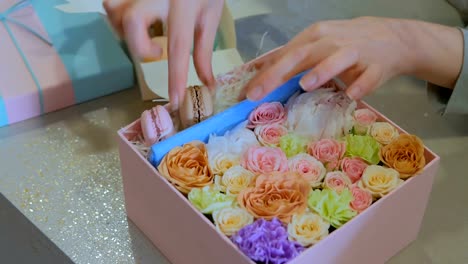 Professional-florist-making-gift-box-with-flowers,-cake-macarons-at-flower-shop