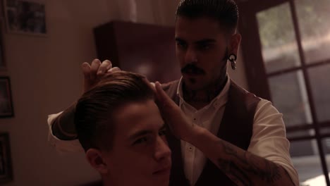 Hipster-barber-styling-teenage-boy's-hair-at-old-fashioned-hair-salon