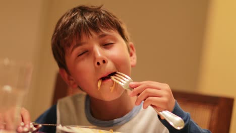 Komisch-übertrieben-Ausdrücken-des-jungen-Nudeln-zum-Abendessen-zu-genießen.-Expressive-Kind-essen-Spaghetti-Nudeln-zum-Abendessen.