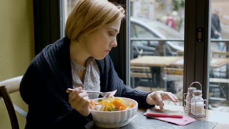 una-mujer-comiendo-una-ensalada-y-comprobar-nuevos-mensajes-en-su-teléfono-inteligente