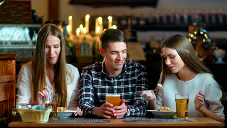 Glückliche-Freunde-sitzen-im-Café-beim-Essen-und-Trinken-von-Alkohol.