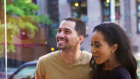 Smiling-couple-looking-at-clothes-in-shop-window,-close-up