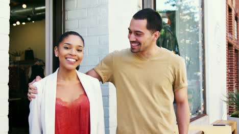 Pareja-de-jóvenes-hispanos-sonriendo-a-la-cámara-fuera-de-su-tienda