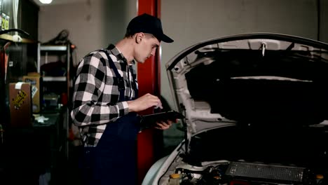 Mechanic-inspects-the-car-undercarriage-way-with-a-digital-tablet