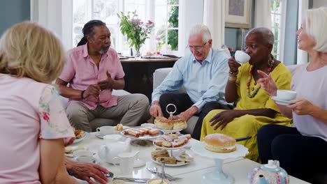 Gruppe-von-Senioren-Freunde-Afternoon-Tea-zu-Hause-gemeinsam-genießen