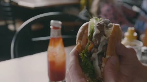 Man-Dips-Double-Meat-Patty-Burger-in-Ketchup-Before-Taking-Large-Bite-Closeup