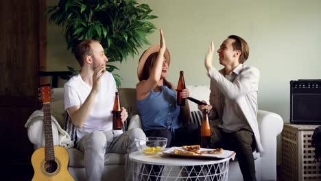 Nervous-fans-attractive-young-people-are-watching-match-on-TV-and-cheering-over-beer-and-snacks-then-celebrating-success-with-high-five-and-excited-gestures.