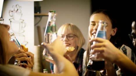 Amigos-felices-del-multiétnicos-haciendo-un-brindis-mientras-comen-pizza-en-fiesta-casual.-Gente-joven-pasa-diversión-tiempo-junto