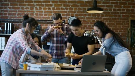 Kolleginnen-und-Kollegen-im-Büro-zusammen-Pizza-Essen