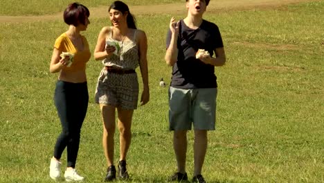 Studenten-Walking-In-The-Park,-genießen-Sie-essen-sandwiches