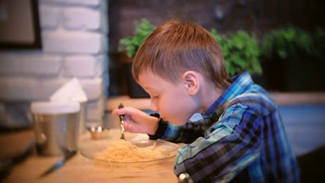 Niño-come-espaguetis-en-el-café-y-TV-de-relojes.