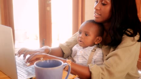 Blogger-de-madre-con-niño-trabajando-desde-su-casa-en-la-computadora-portátil