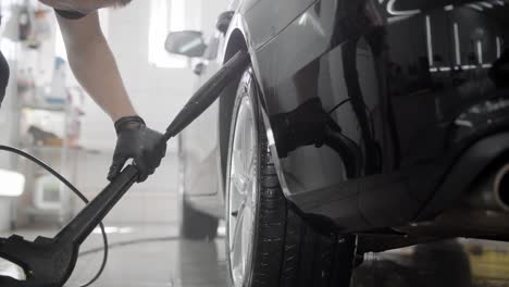 Faceless-person-watering-wheel-in-car-wash